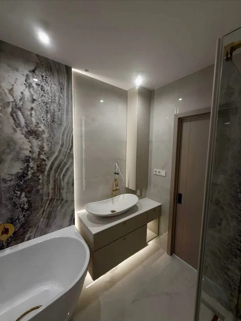 Completed bathroom with marble-effect tiles and a freestanding bath.