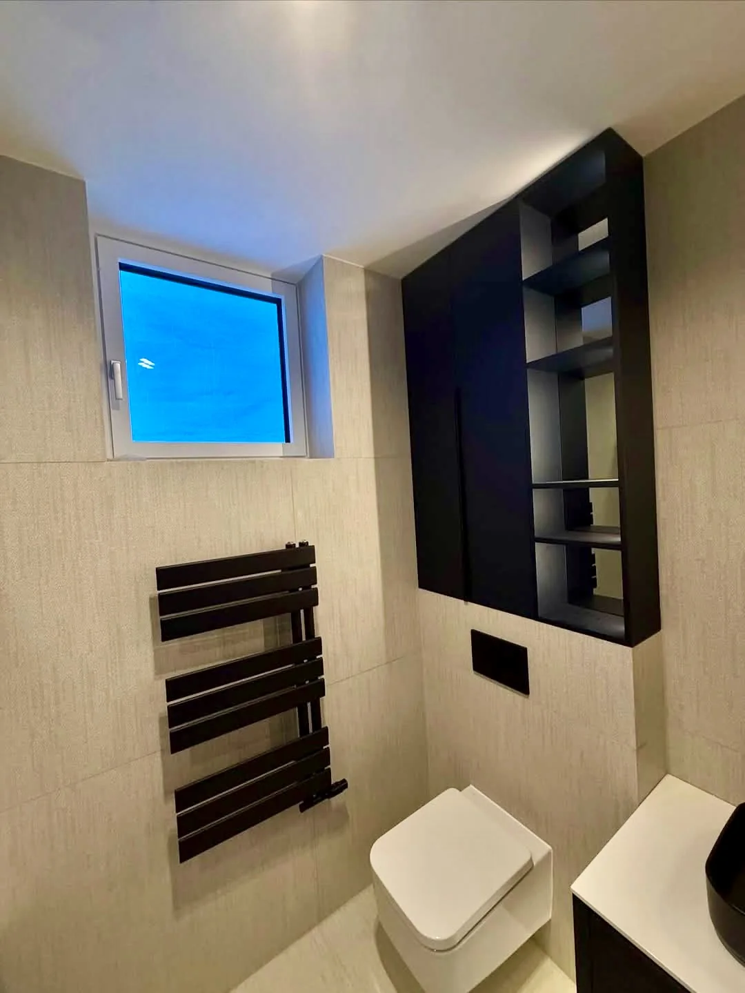 Dark-tiled storage niches in a light bathroom.