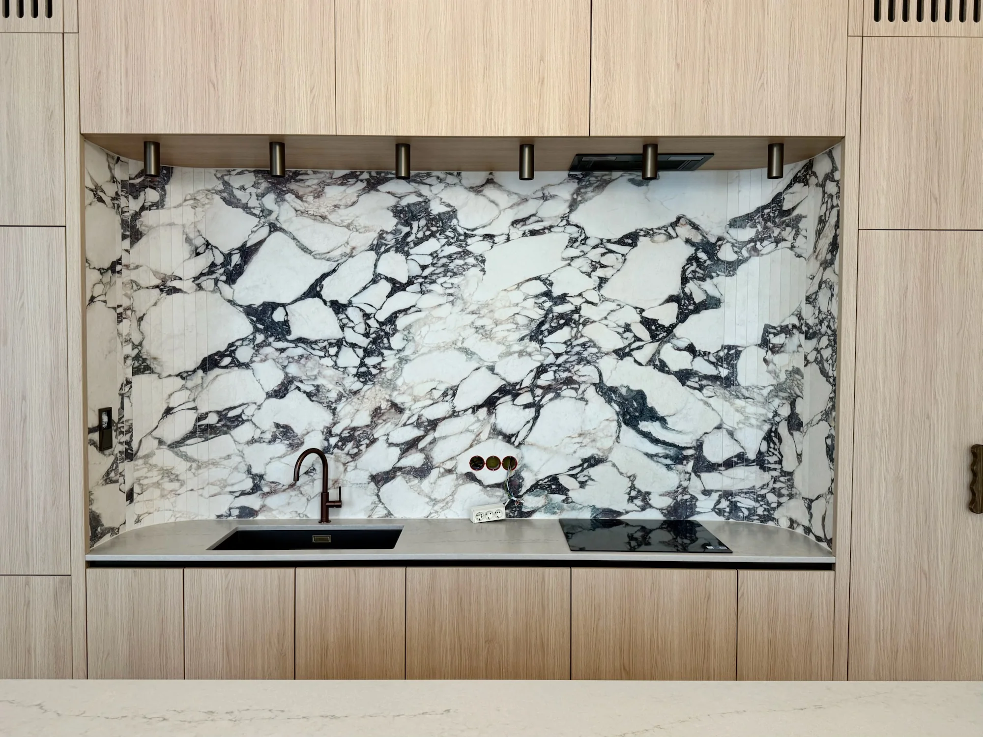 Marble-effect kitchen splashback with light wooden cabinets
