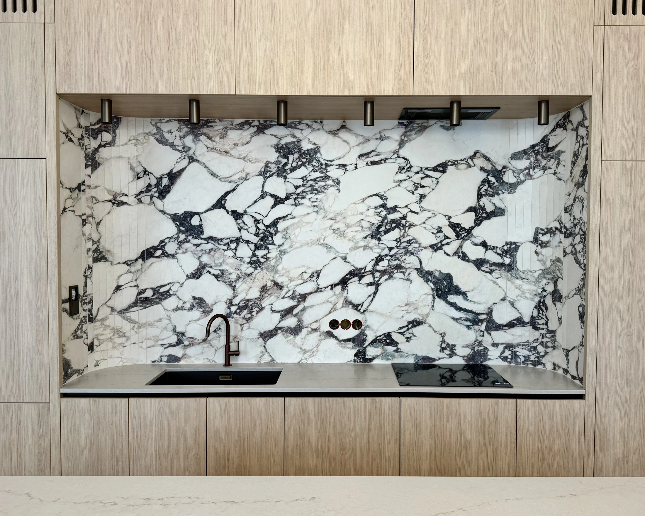 Marble-effect kitchen splashback with light wooden cabinets
